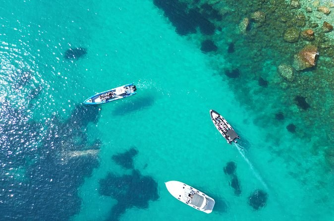 Three small boats at anchor over turquoise water and seagrass, seen from above