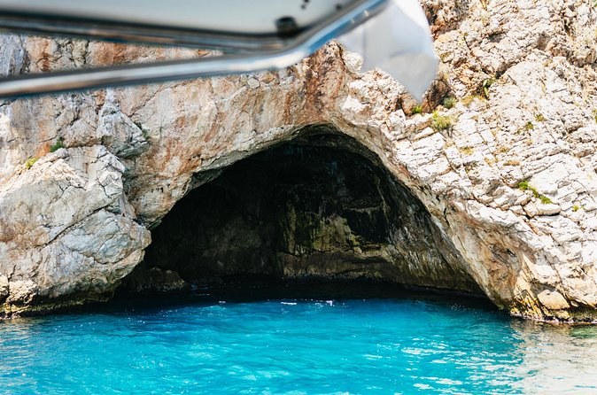 A sea cave opening at water level in pale limestone cliffs