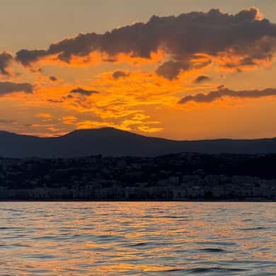 An orange sunset over dark hills, seen from the sea